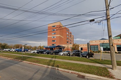 A parking lot with cars and a tall brick building in the background.