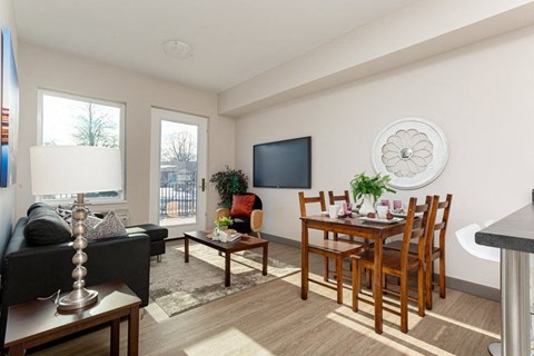 A living room with a black couch, a wooden dining table, and a television.
