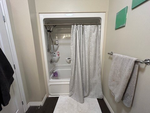 A bathroom with a white shower curtain and a white rug.