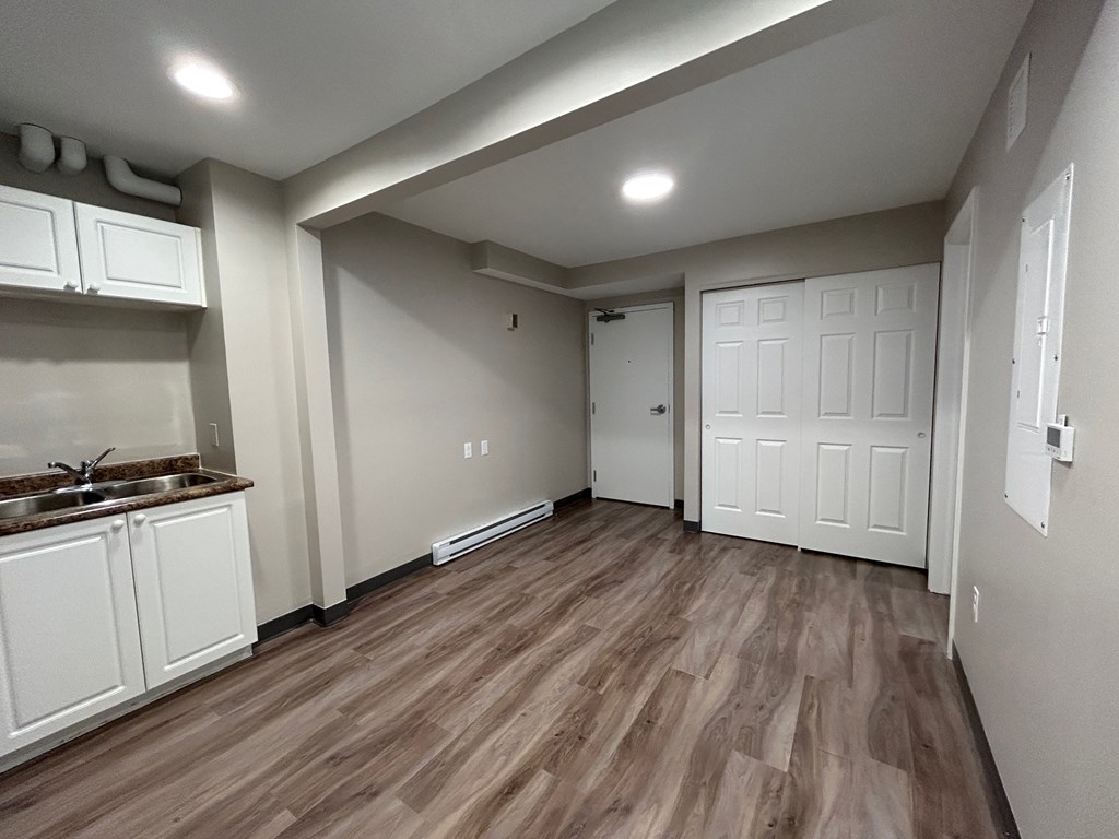 A kitchen with white cabinets and a brown floor.