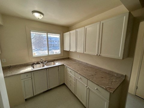 a kitchen with white cabinets and a sink and a window