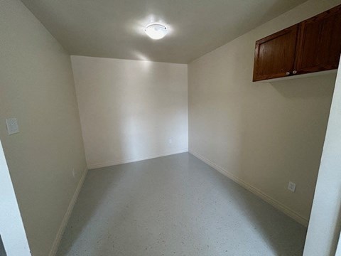 an empty room with white walls and a cabinet