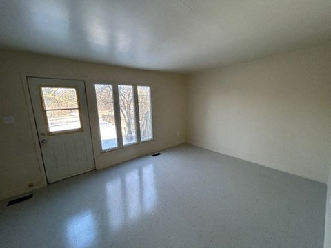 an empty living room with a door and window
