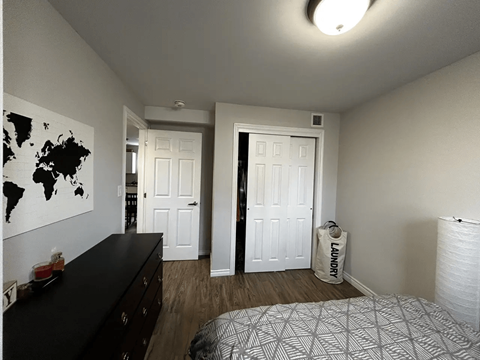 A bedroom with a black dresser and a world map on the wall.