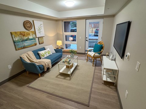 A living room with a blue couch, a coffee table, and a flat screen TV.
