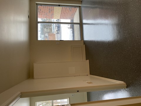 A white desk with a window above it.