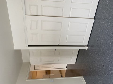A white cabinet with a mirror above a wooden table.