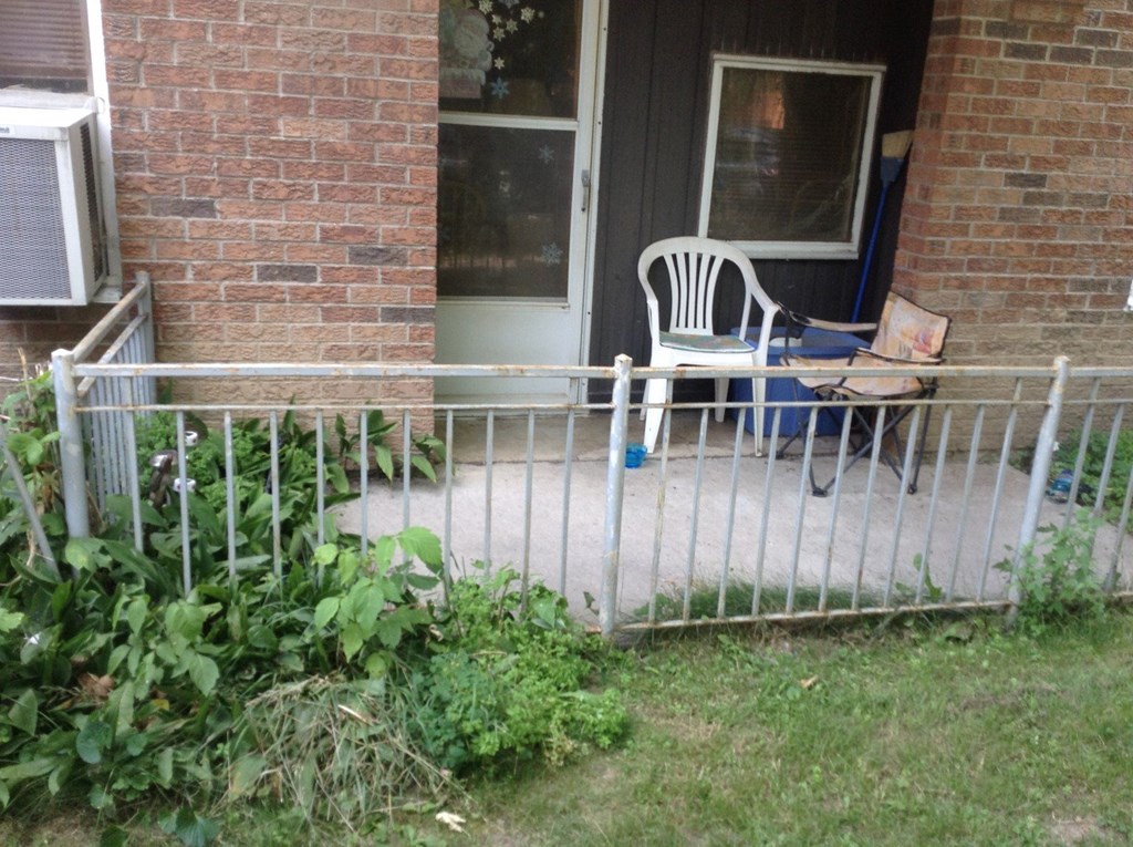 A white chair is on a porch with a metal railing.