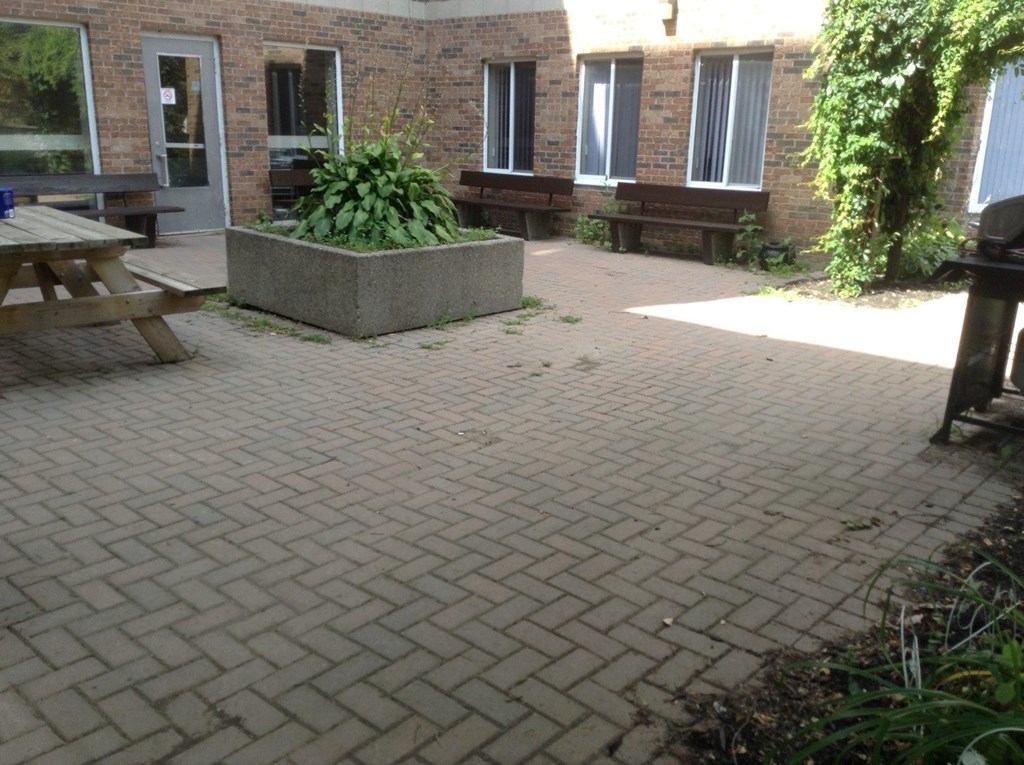A patio with a table and benches outside a brick building.