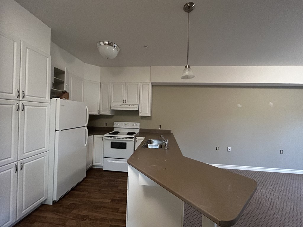 an empty kitchen with white appliances and white cabinets