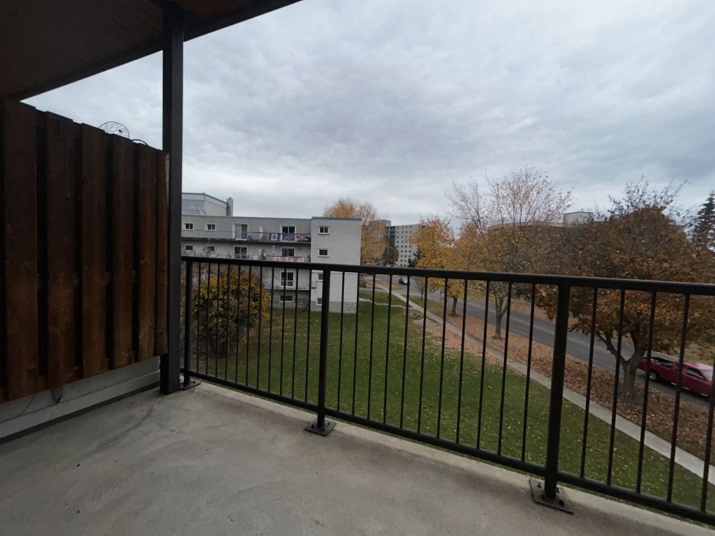 a balcony with a black railing and a grass field