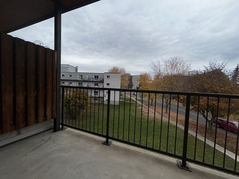 a balcony with a black railing and a grass field