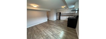 A kitchen with a black fridge and wooden flooring.