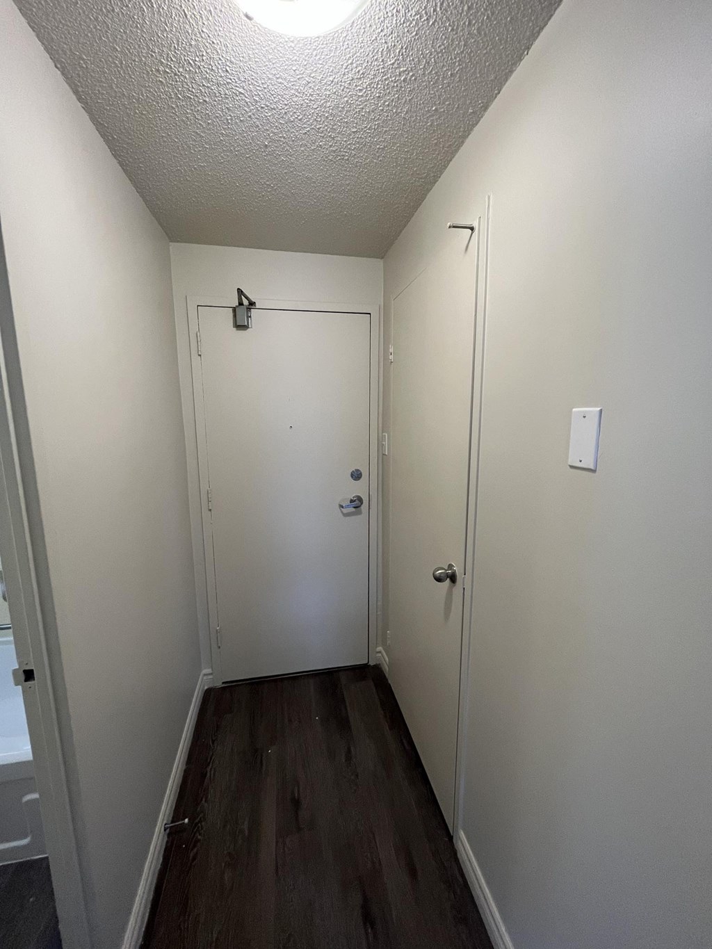 A hallway with a door on the left and a door on the right.