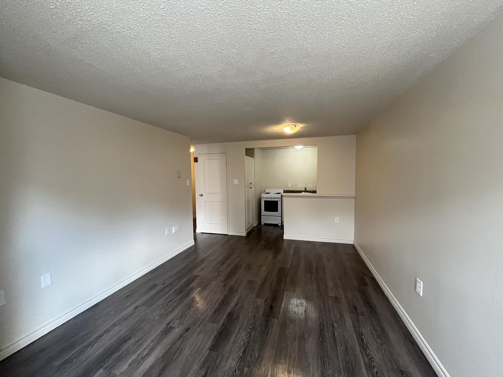 A spacious room with wood flooring and white walls.