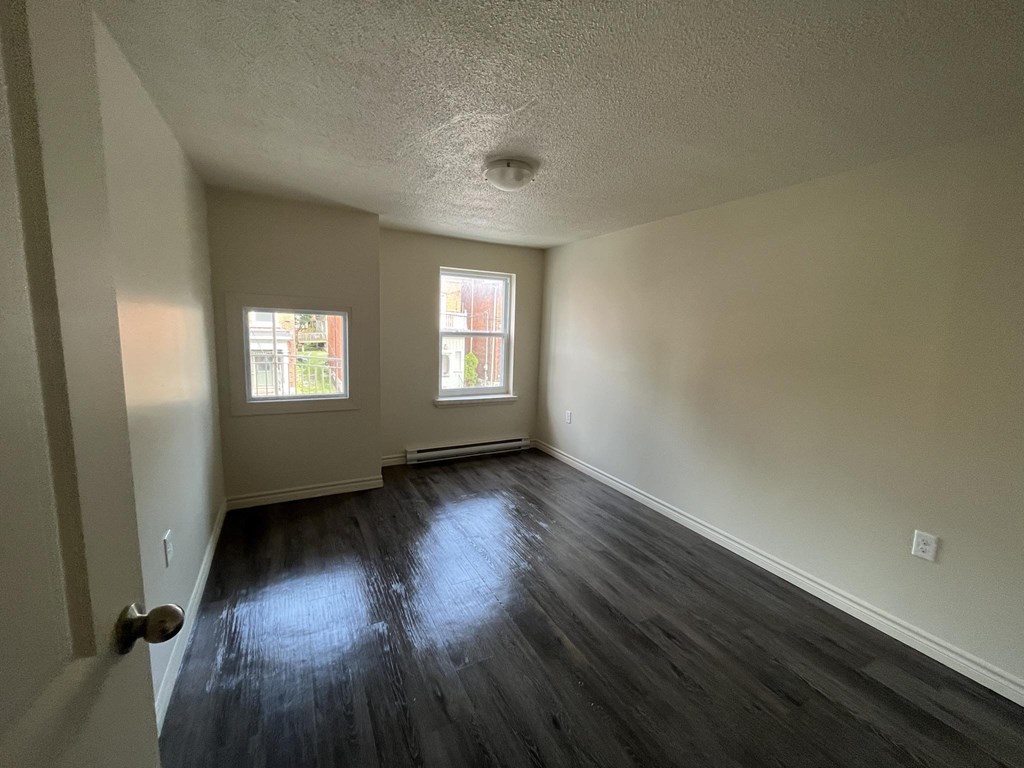 A room with a wooden floor and two windows.