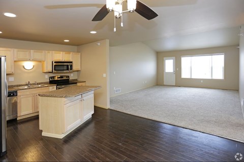 A spacious kitchen with wooden floors and a ceiling fan.