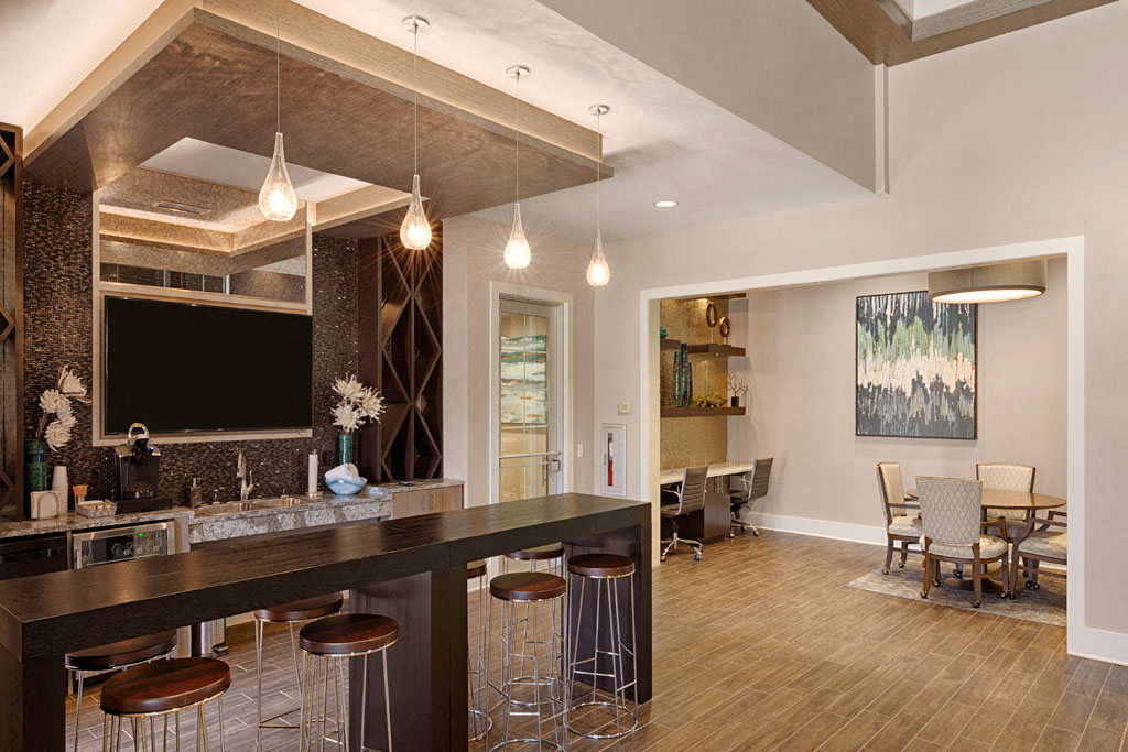 Bar area with flat-screen TV, coffee maker, mini fridge and seating; adjacent to resident lounge with desks, tables and chairs