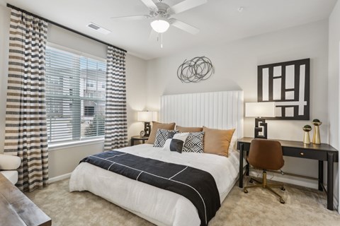 a large bedroom with a ceiling fan and large window