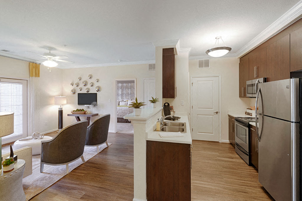 Kitchen with upgraded quartz countertops, wood plank floors and stainless steel appliances; door to washer/dryer area; open to living room