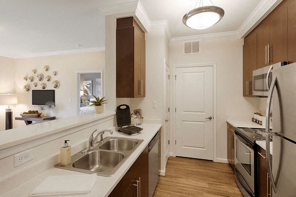 Open concept designer kitchen with upgraded quartz countertops, stainless steel appliances and wood plank floors; kitchen pantry available in select homes; open to living room