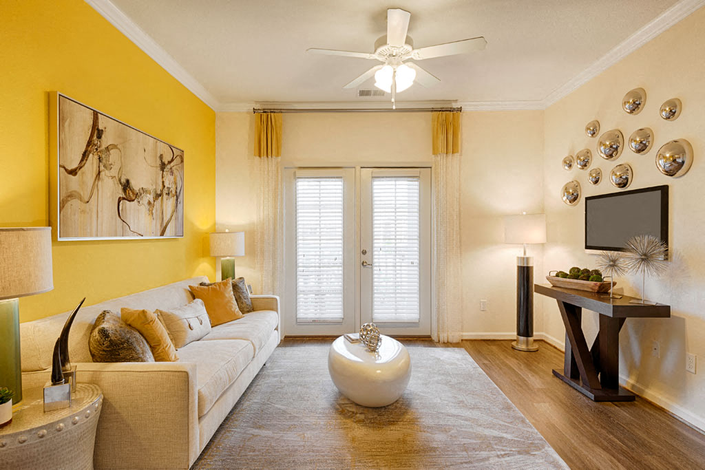 Living room with couch; door to patio or balcony; ceiling fan
