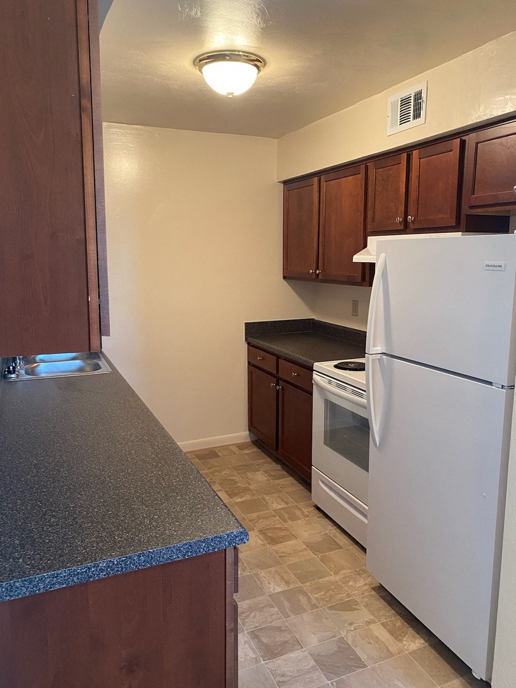 a kitchen with white appliances and a counter top and a refrigerator