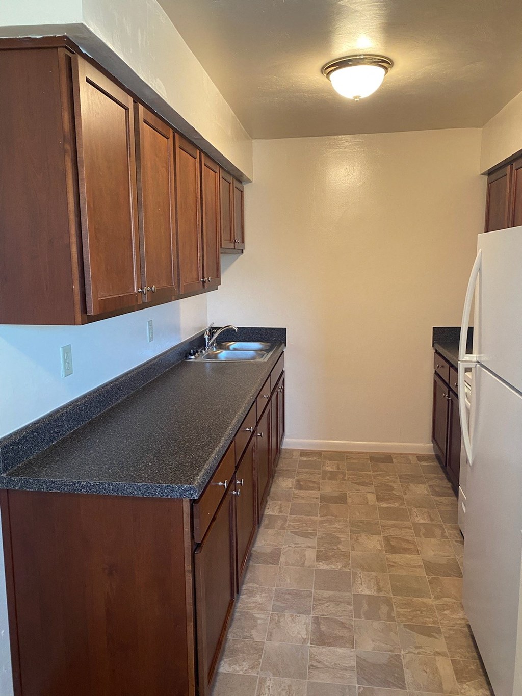 an empty kitchen with a counter top and a refrigerator