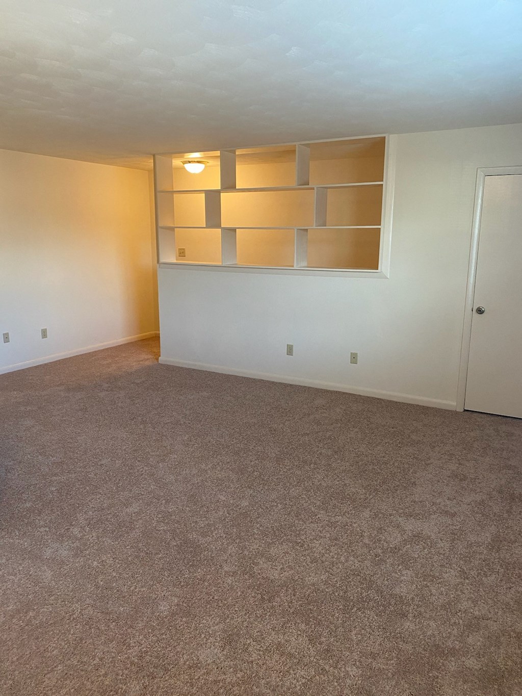 an empty living room with a white wall and a window