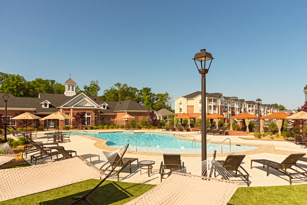 Pool surrounded by chairs and cabanas; hammock park