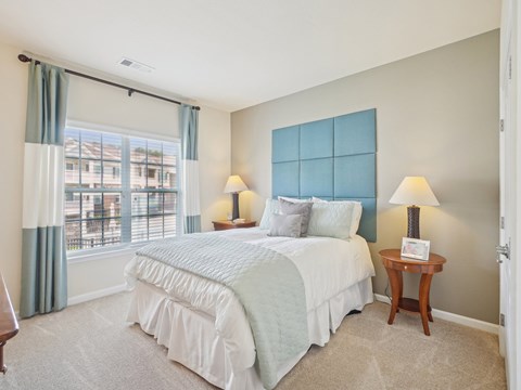 A bedroom with a large bed and a window with a view of a building outside.