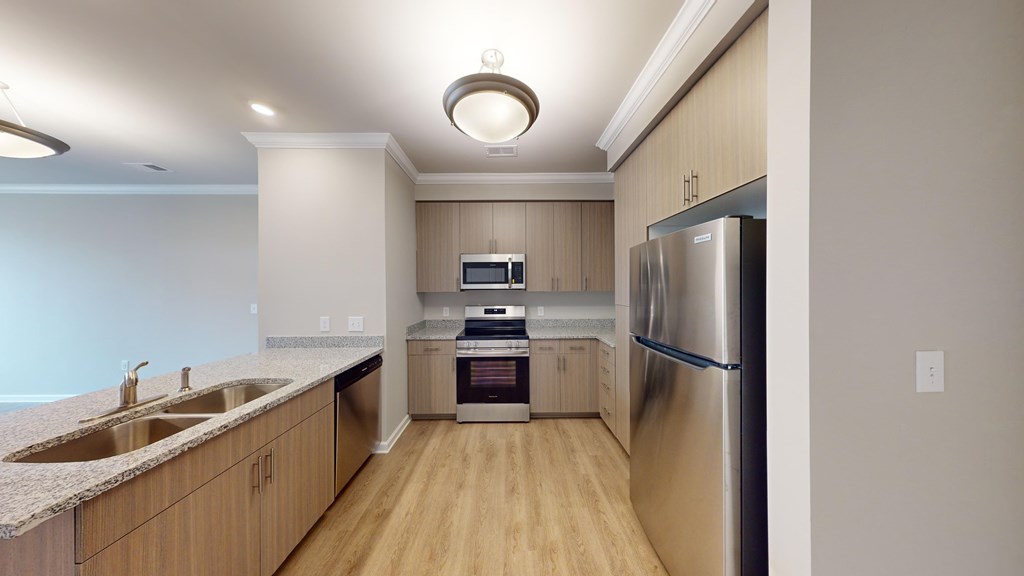 A kitchen with a refrigerator, sink, and microwave.