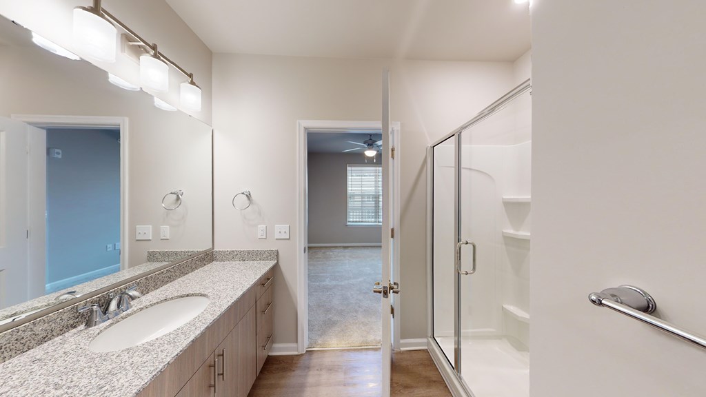 A bathroom with a sink, mirror, and shower.