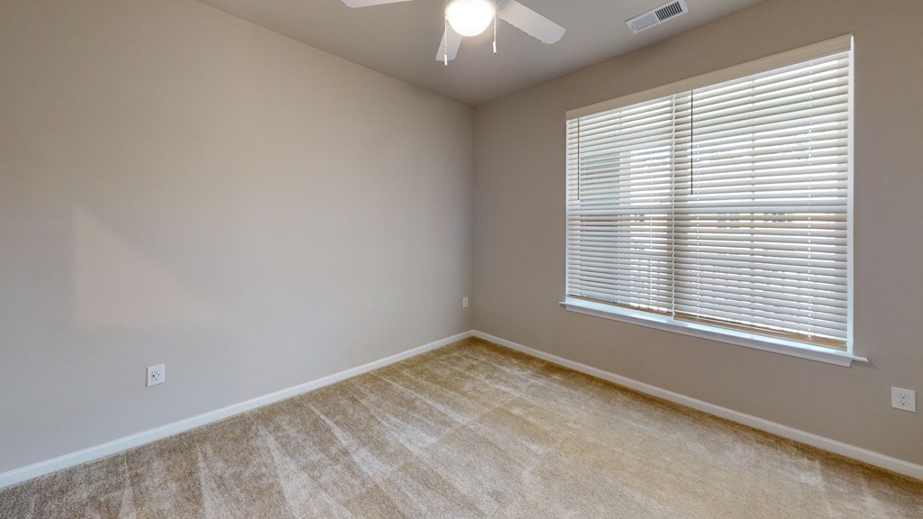 an empty bedroom with a large window and a ceiling fan