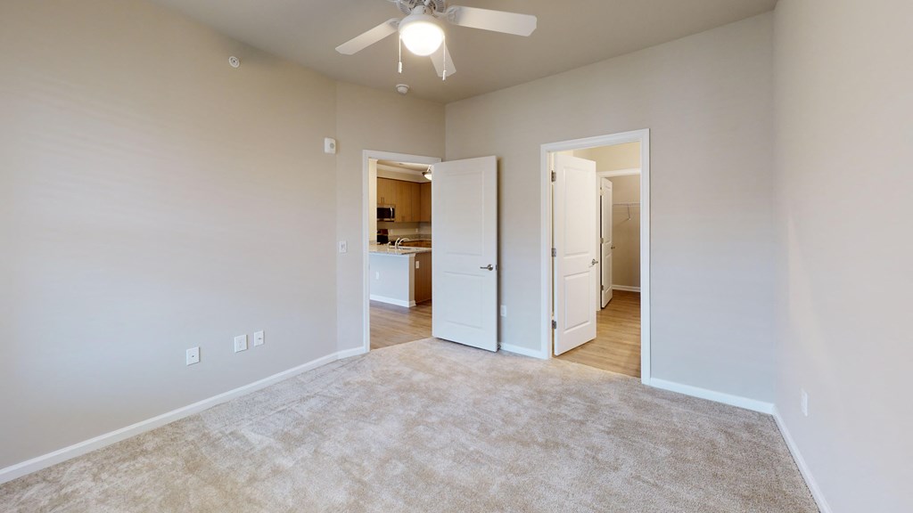 a spacious living room with carpet and a ceiling fan