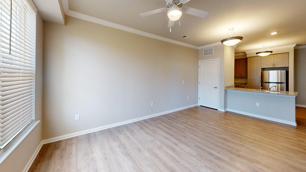 an empty living room with a ceiling fan and a kitchen