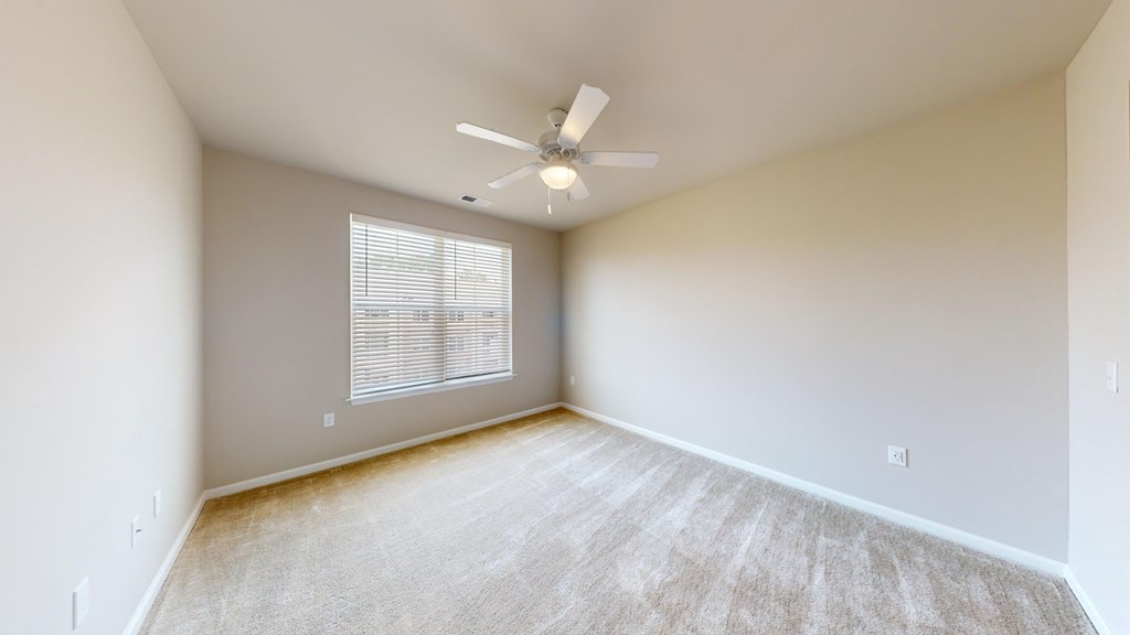 an empty living room with a ceiling fan and a window