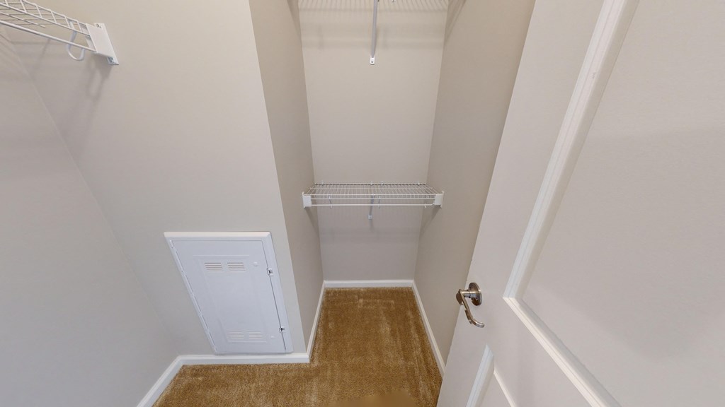 a walk in closet with a white closet door and a white door to a closet