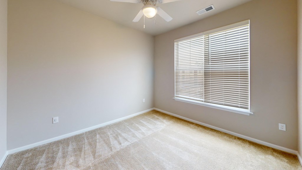 an empty room with a large window and a ceiling fan