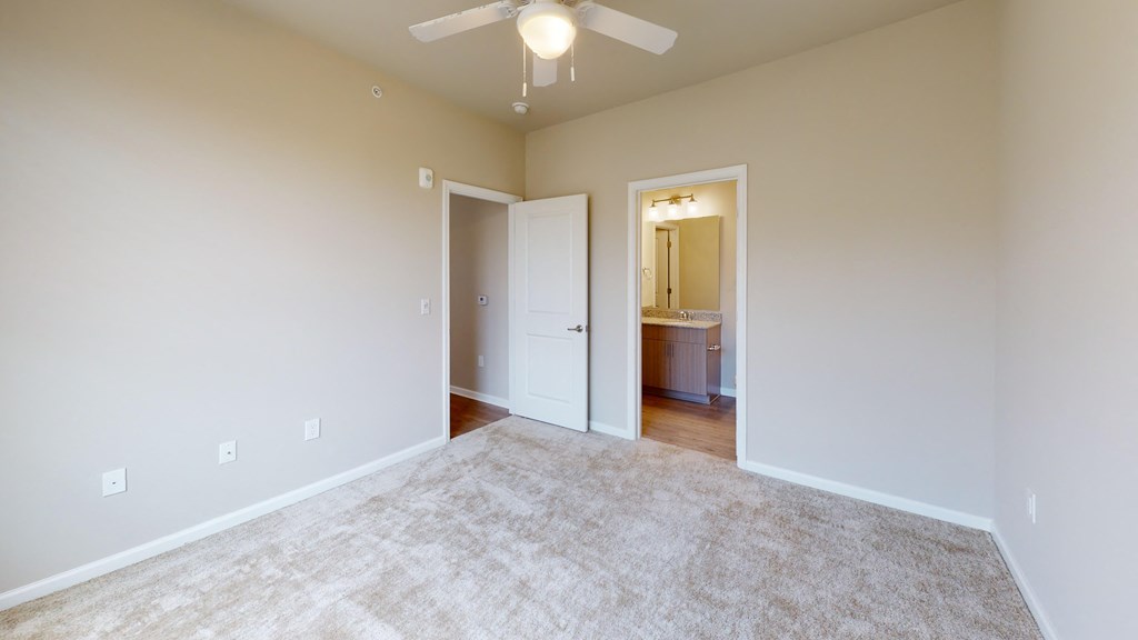 a spacious living room with carpet and a ceiling fan