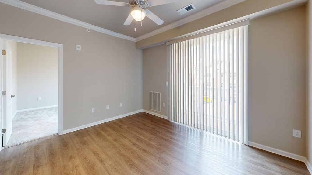 an empty living room with a large window and a ceiling fan