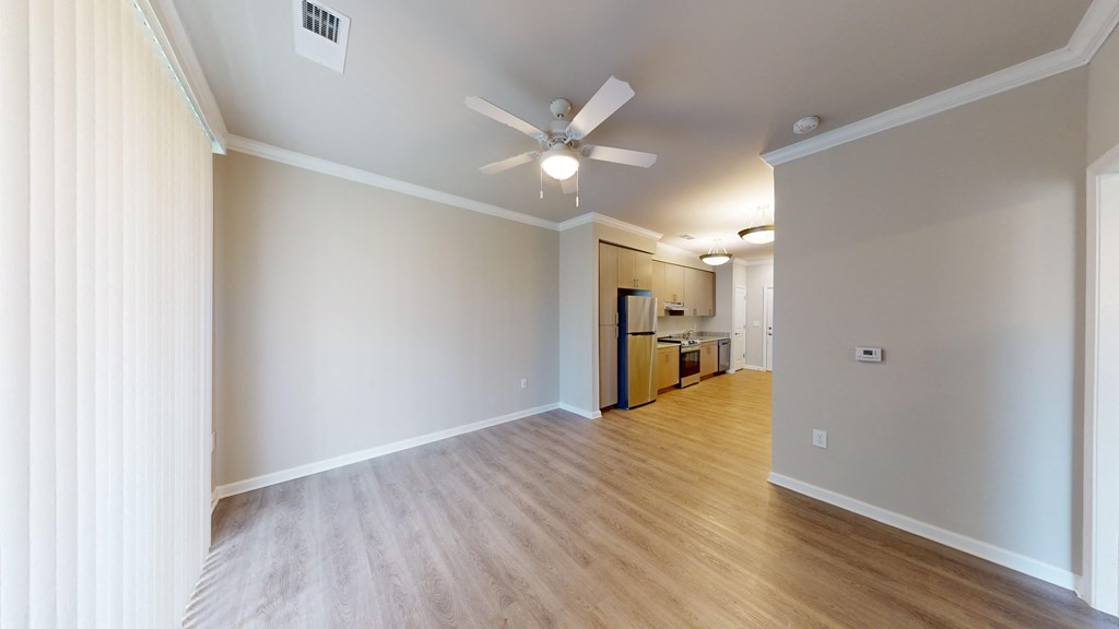 an empty living room with a ceiling fan and wood flooring
