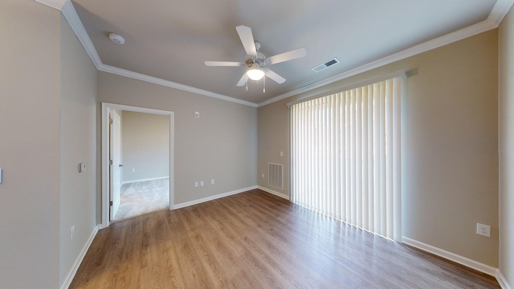an empty living room with wood floors and a ceiling fan