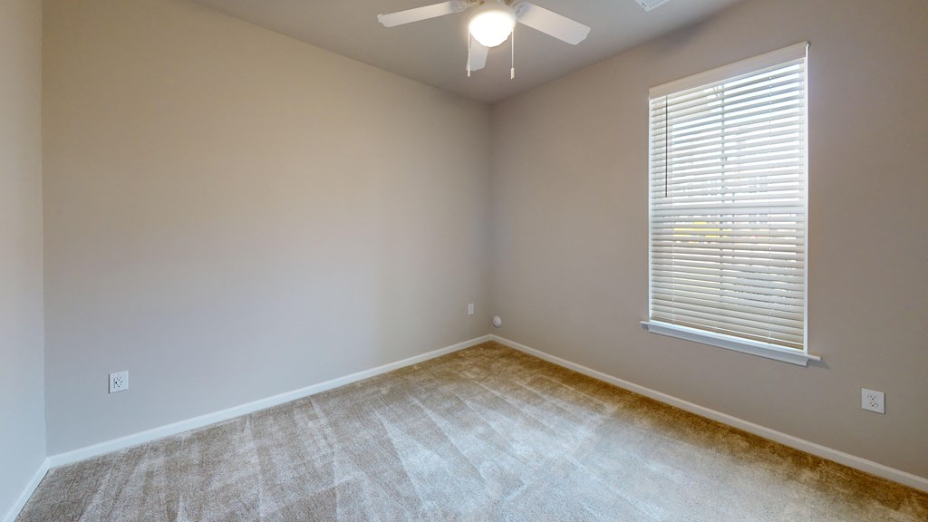 an empty room with a large window and a ceiling fan