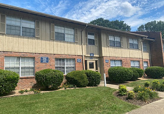 the front of a building with a lawn and shrubs