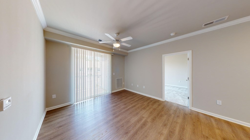 an empty living room with wood floors and a ceiling fan