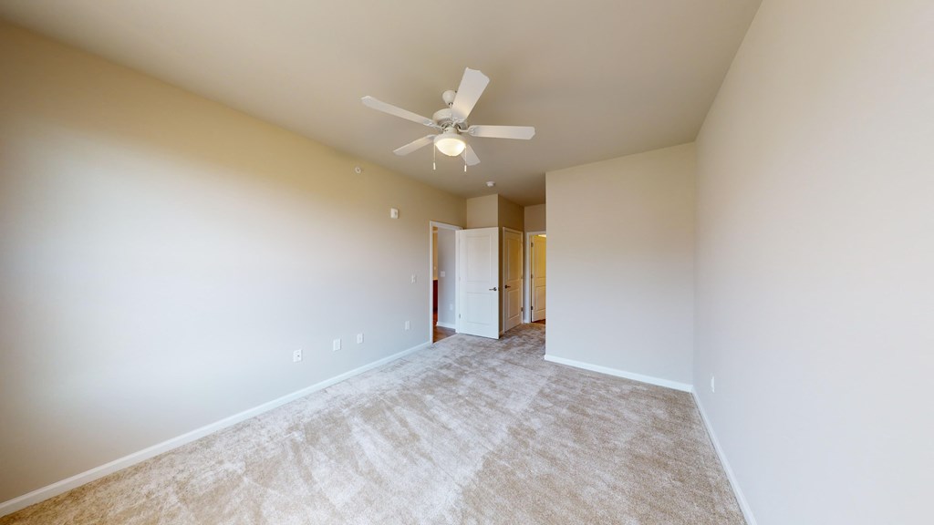 a spacious living room with white walls and a ceiling fan