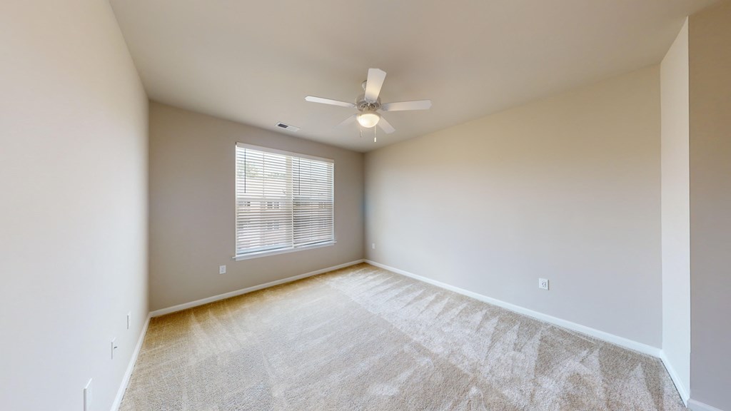 an empty living room with a ceiling fan and a window