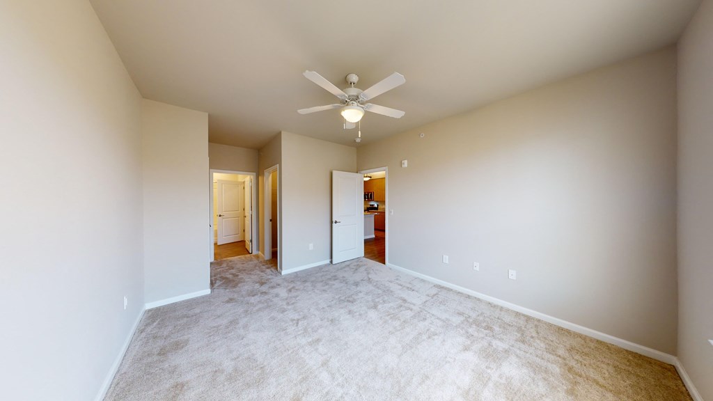 a spacious living room with a ceiling fan and carpet