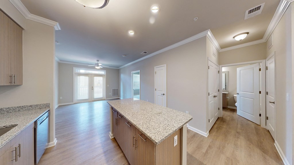 an open kitchen and living room with white doors and a granite counter top